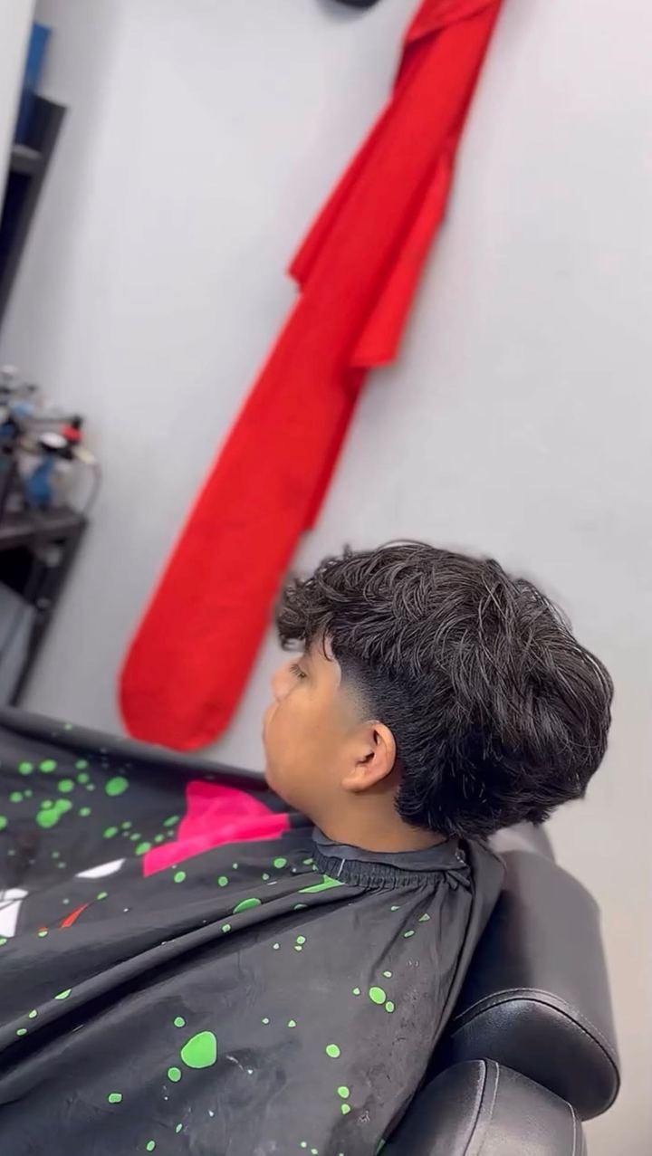 Side view of a client in the barber chair with a wavy textured top and faded sides