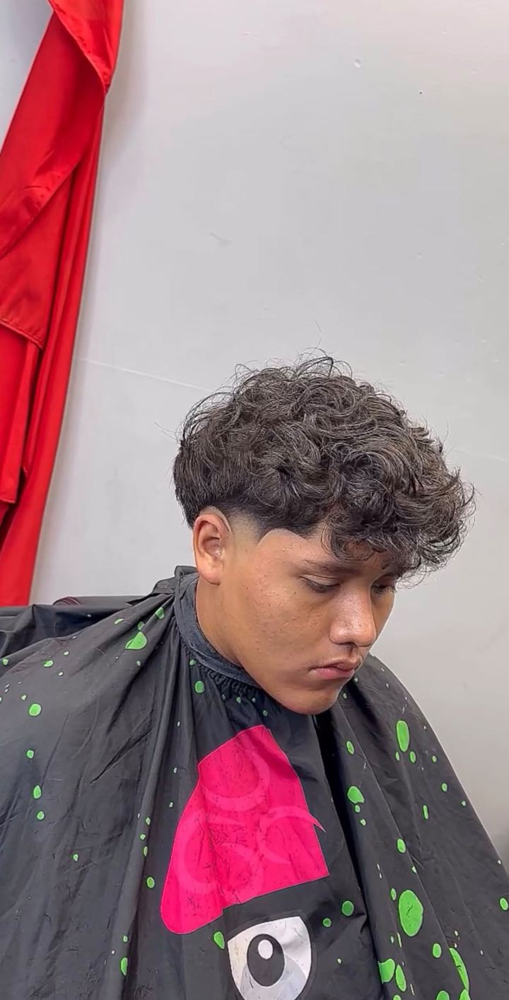 Client with a curly textured top and a taper fade on the sides